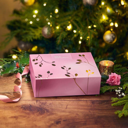 Purple gift wrapping box with gold leaves in front of chrismas tree