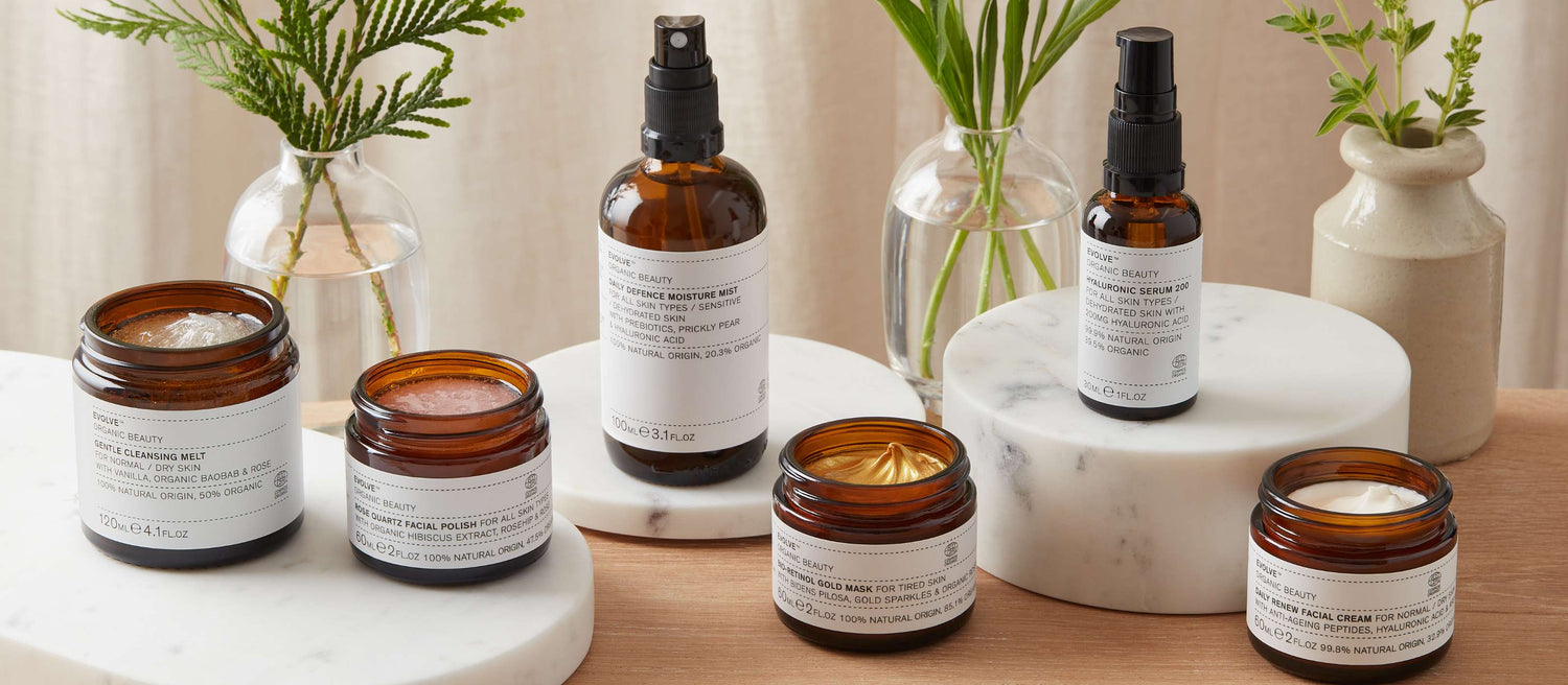 evolve organic skincare bestsellers on marble trays with vases of greenery behind