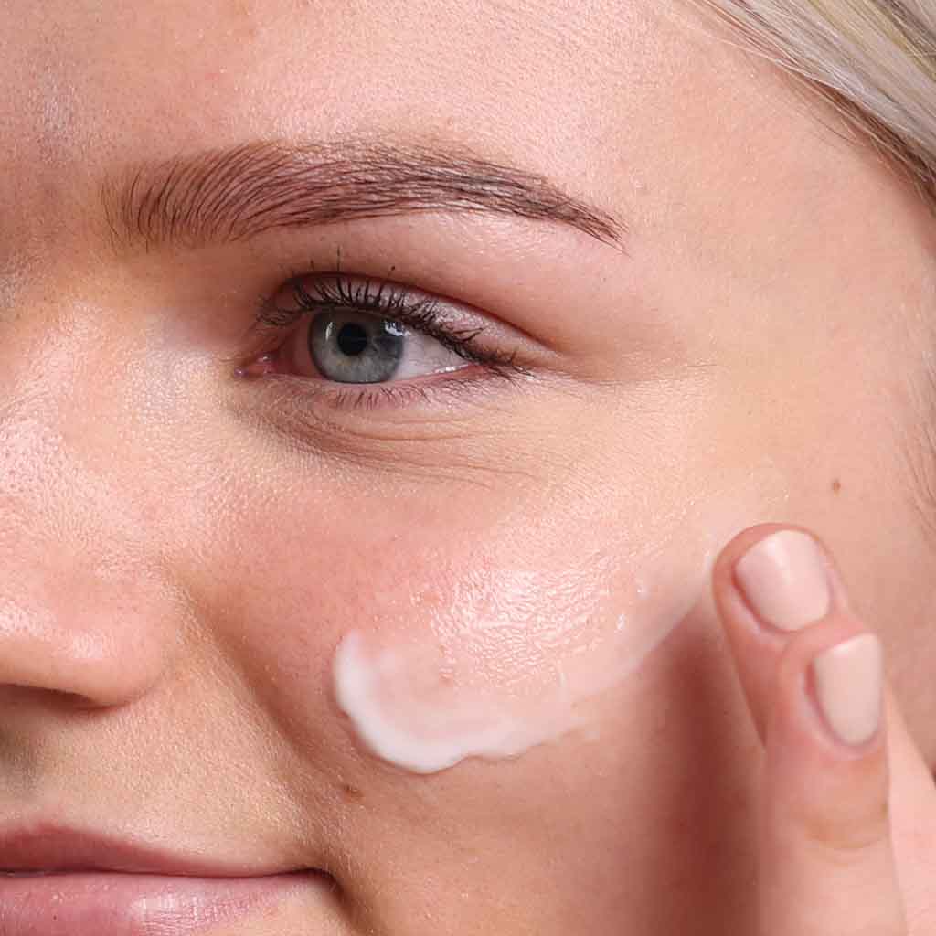 skincare model moisturising face with organic face cream for acne prone skin